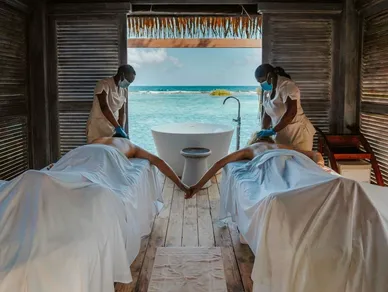 Two women are getting a foot massage in front of the ocean.