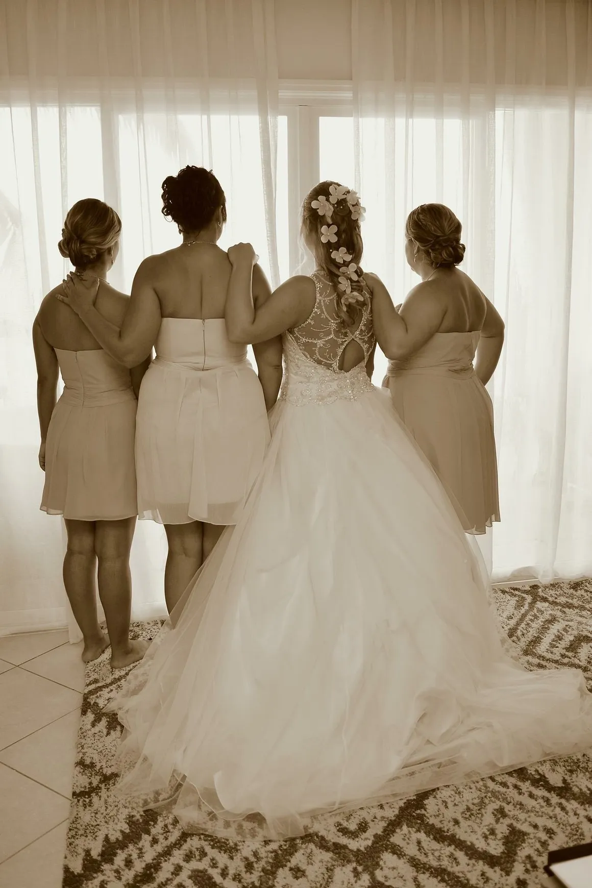 A bride and her bridesmaids in front of the window.