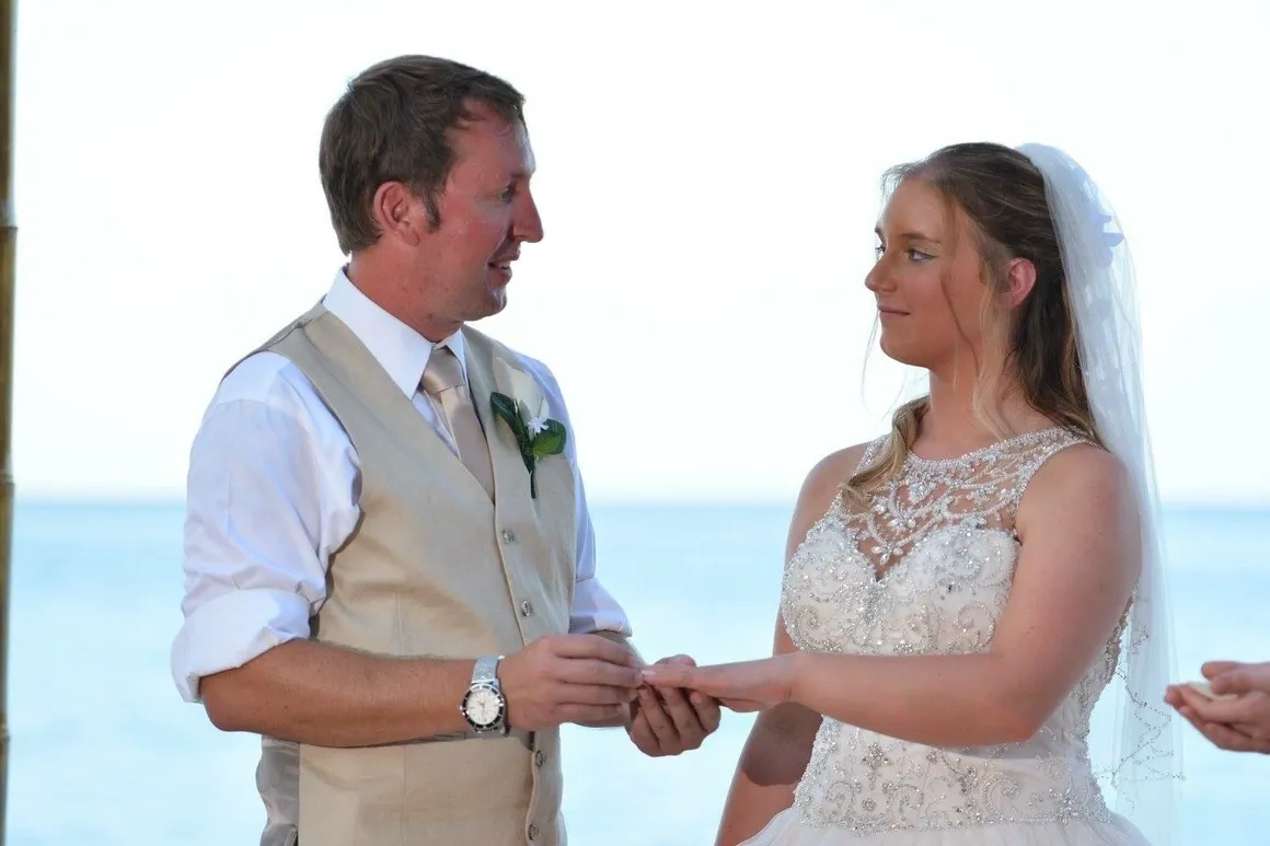 A man and woman holding hands on the beach.