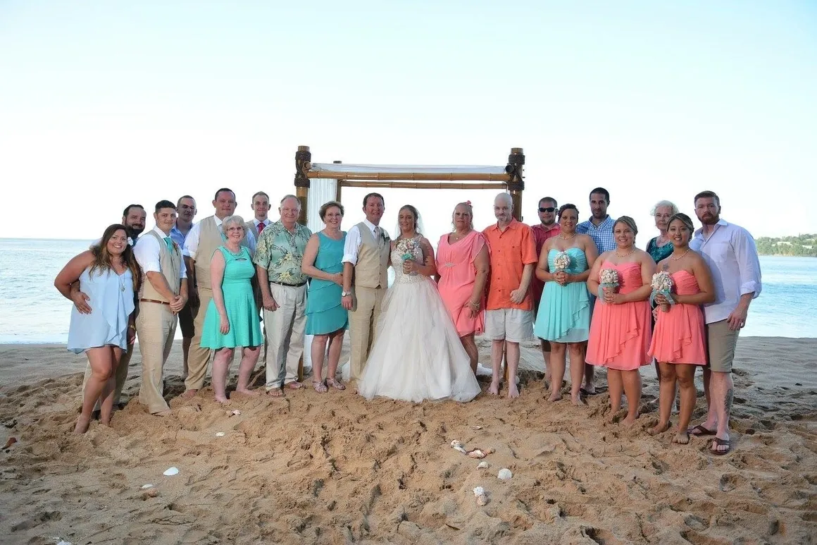 A group of people standing on top of a sandy beach.