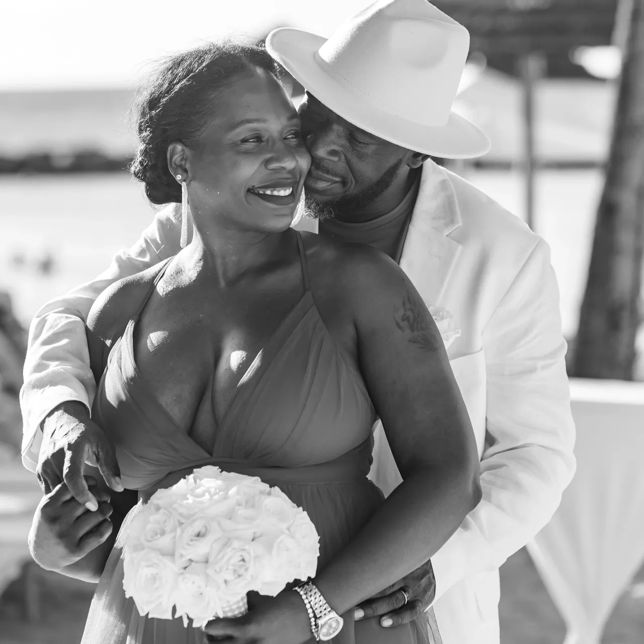 A man and woman embracing in front of the ocean.