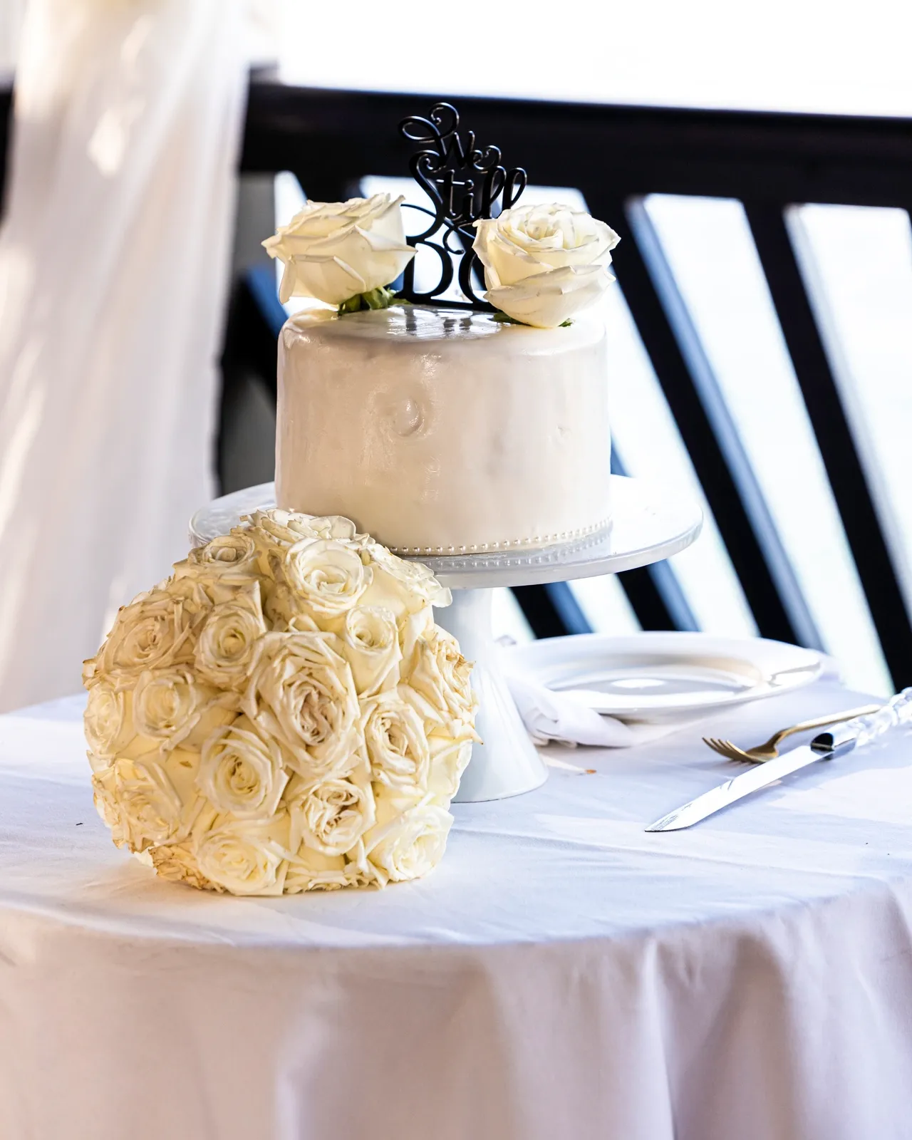 A table with two cakes and a white rose bouquet.