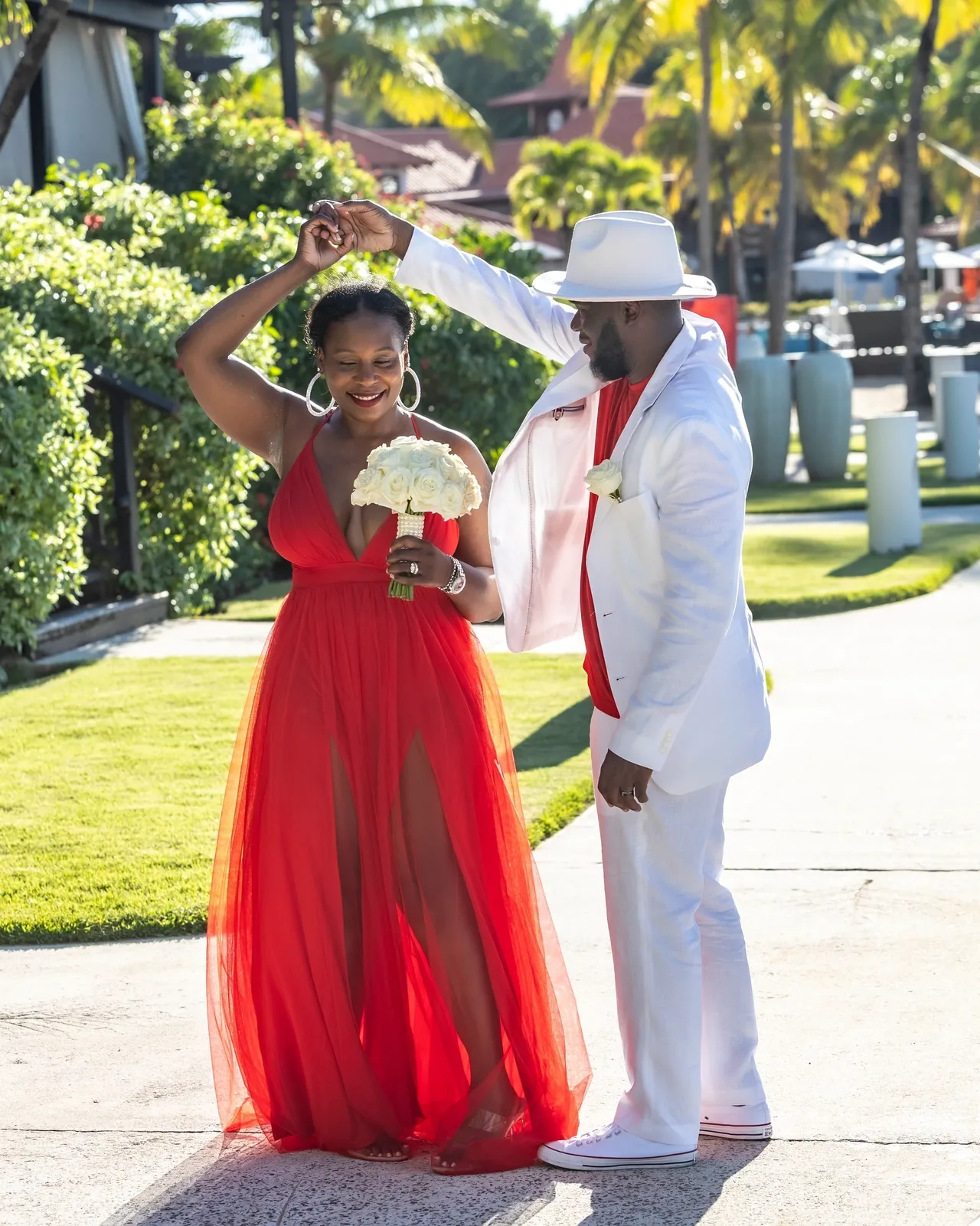 A man and woman dressed in red holding a fan.