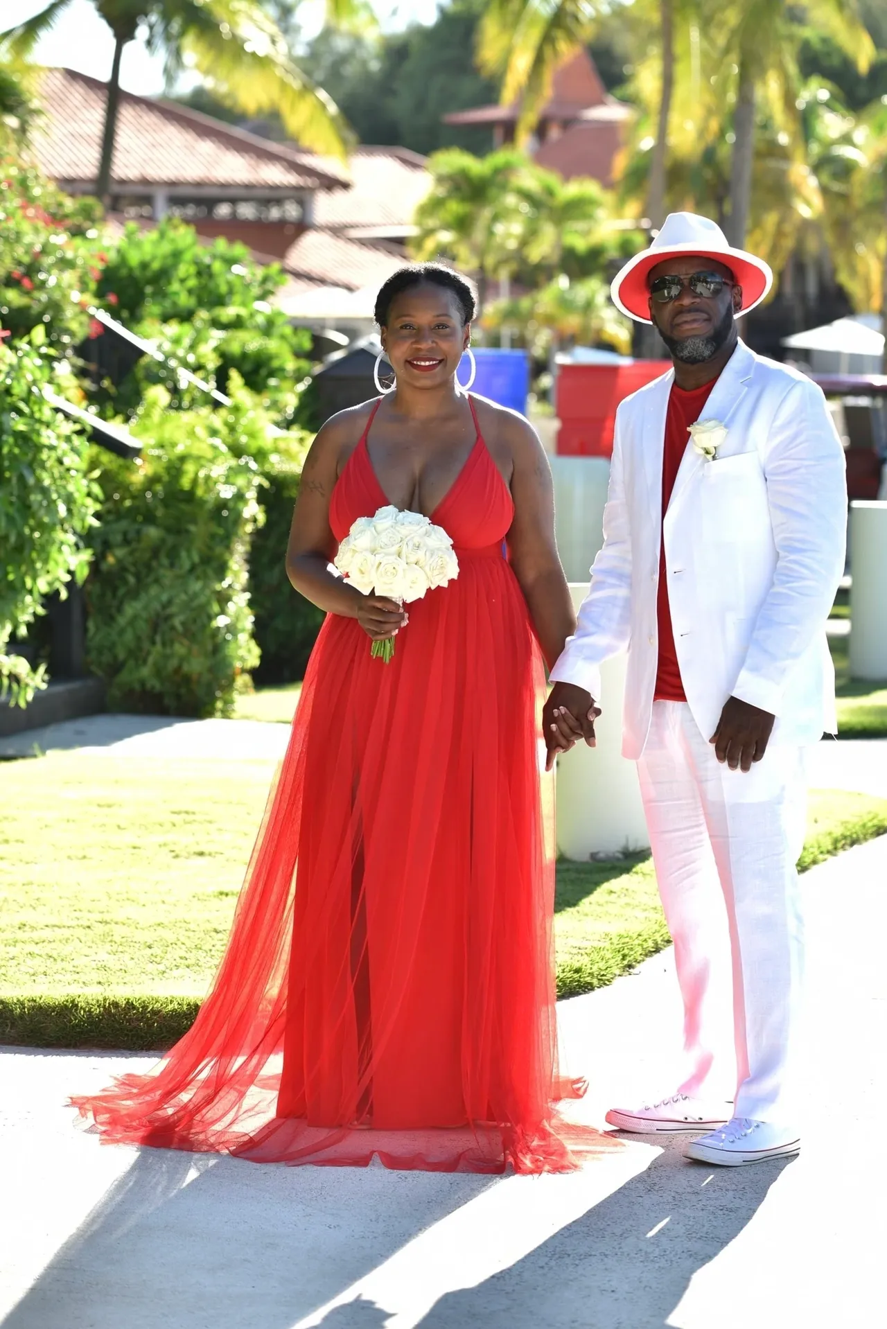 A man and woman in red dress holding hands.