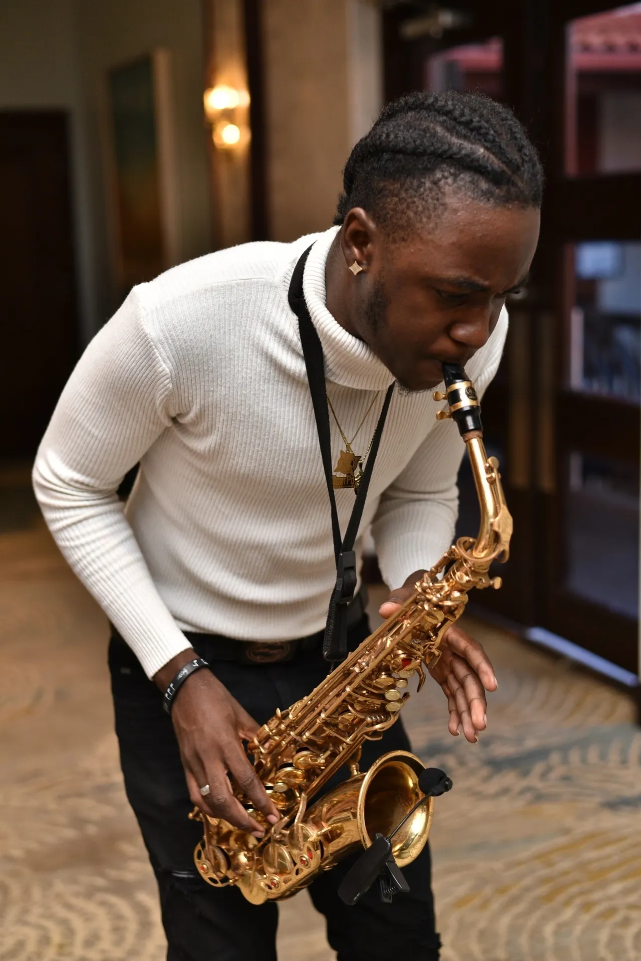 A man playing the saxophone in front of a window.