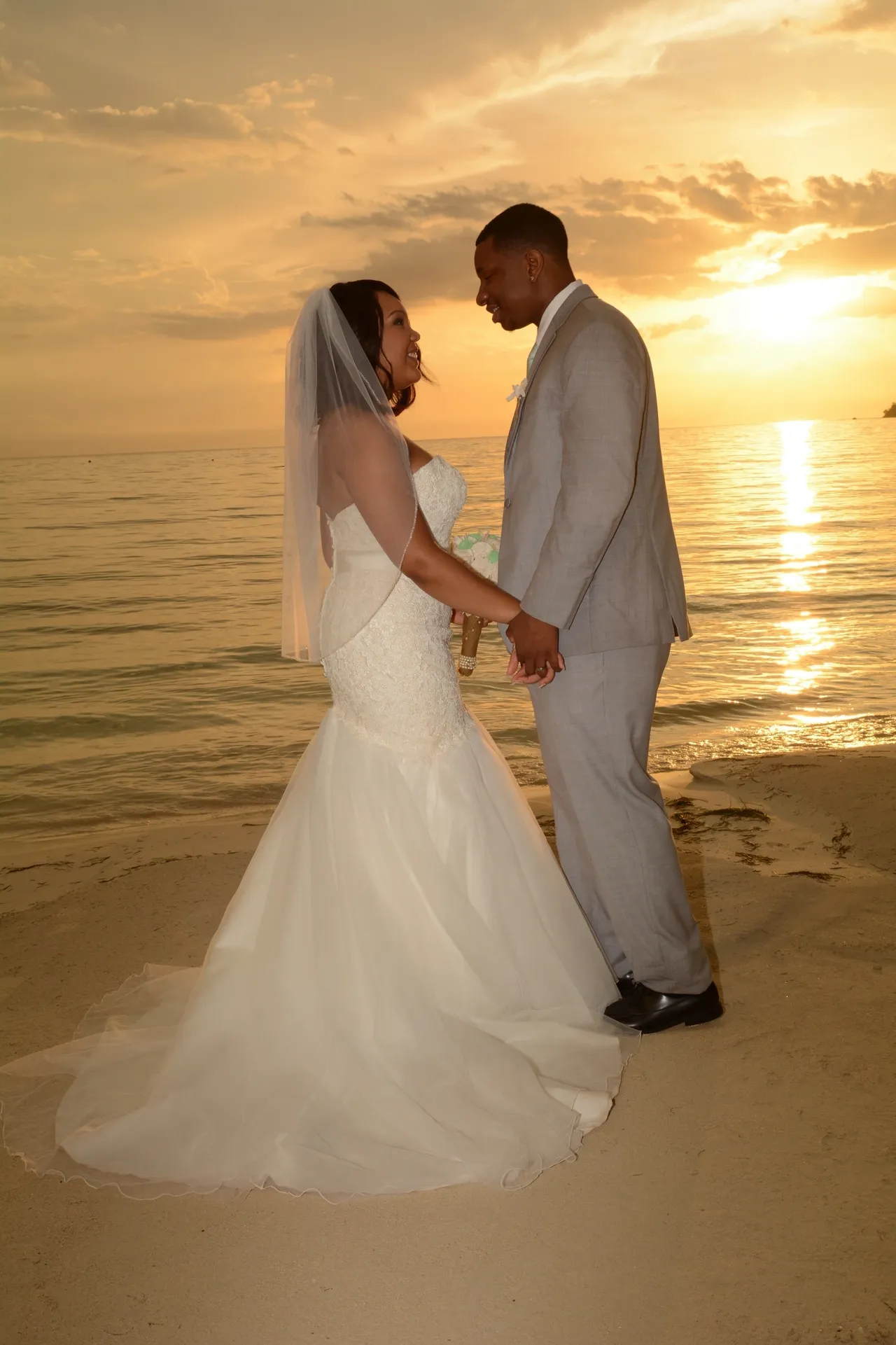 A bride and groom holding hands on the beach