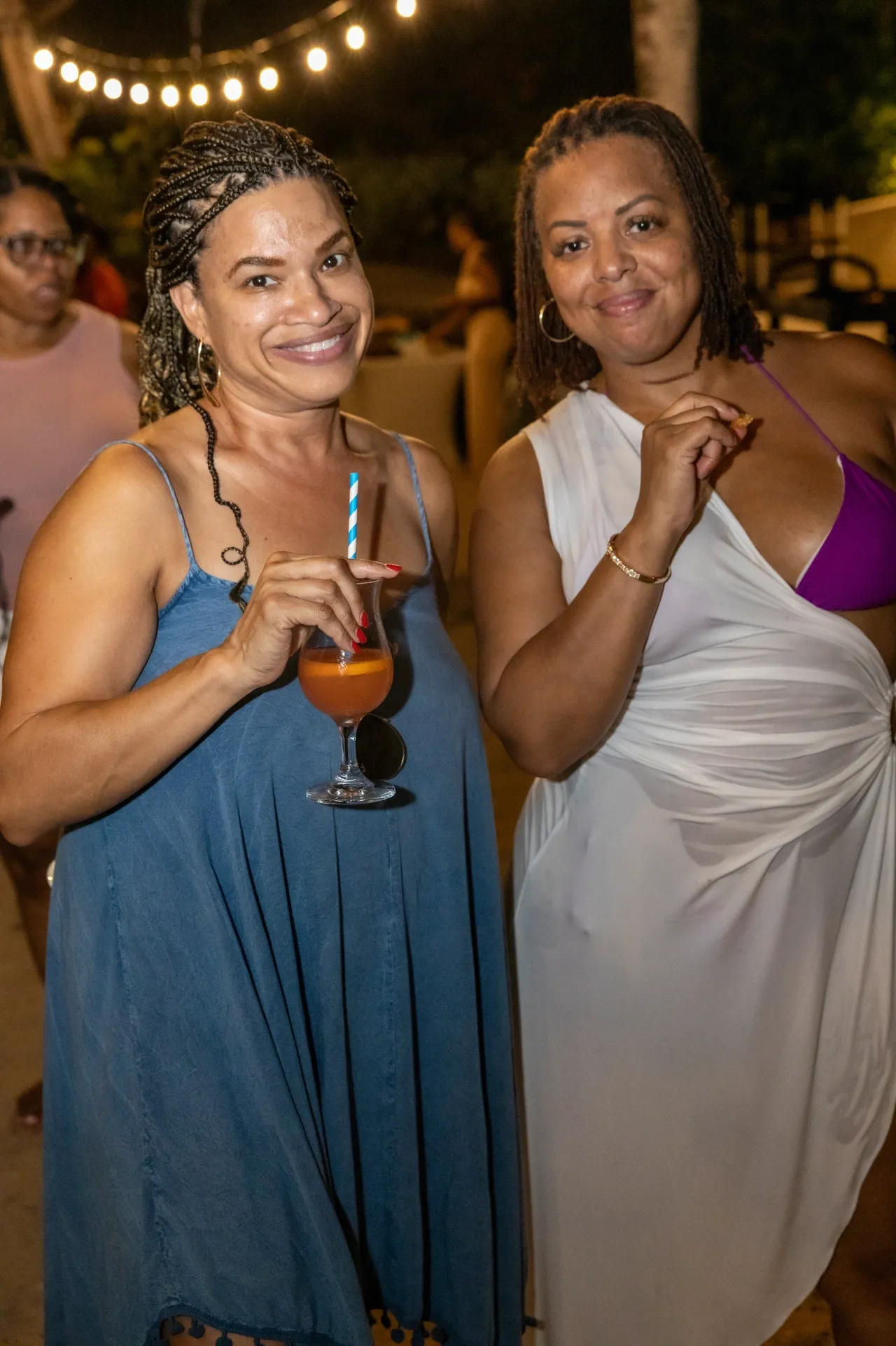 Two women are posing for a picture while holding drinks.