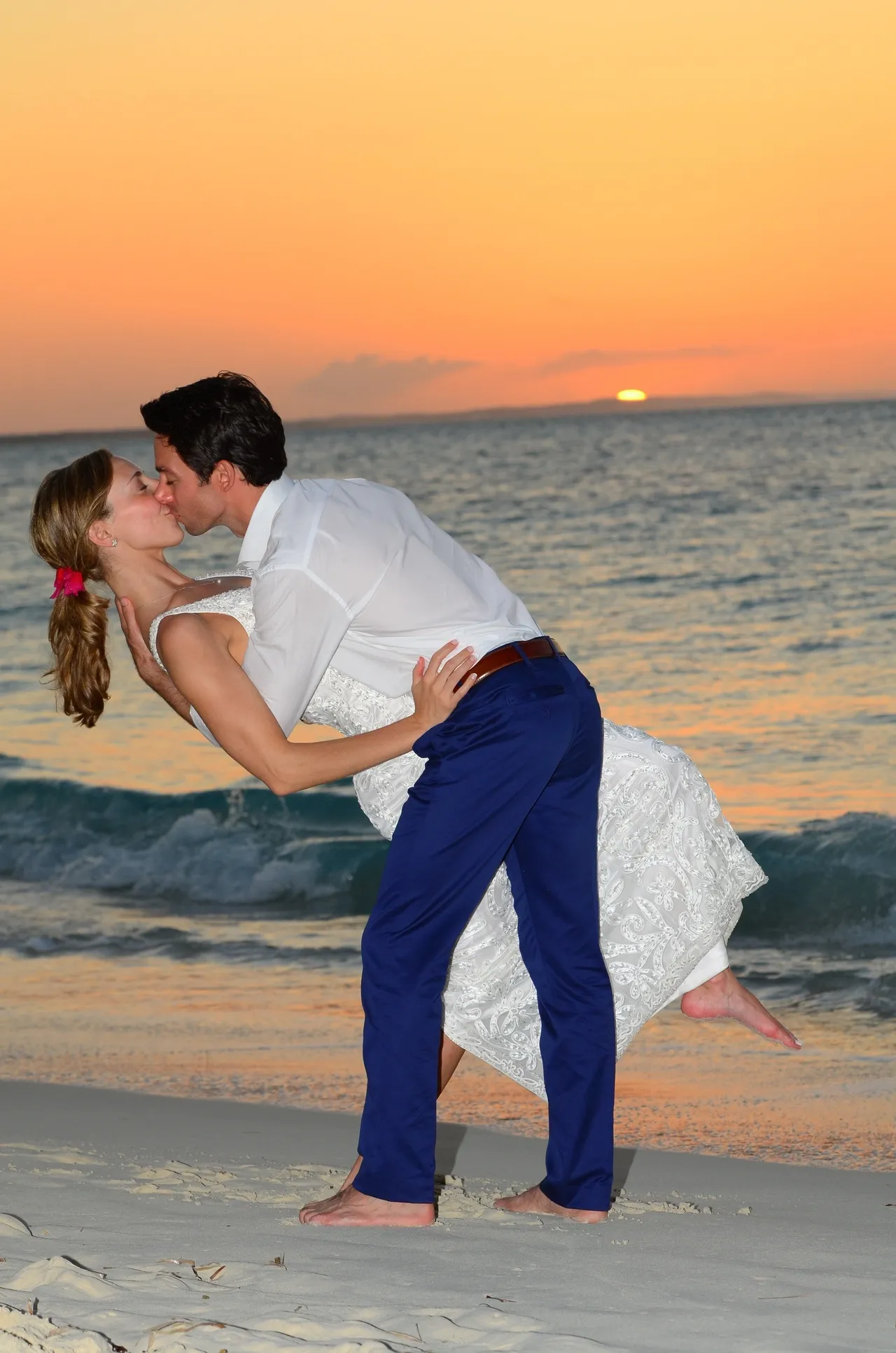 A man and woman kissing on the beach.