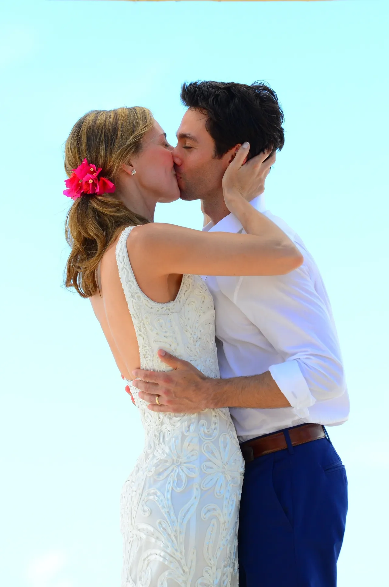 A man and woman kissing in front of the sky.