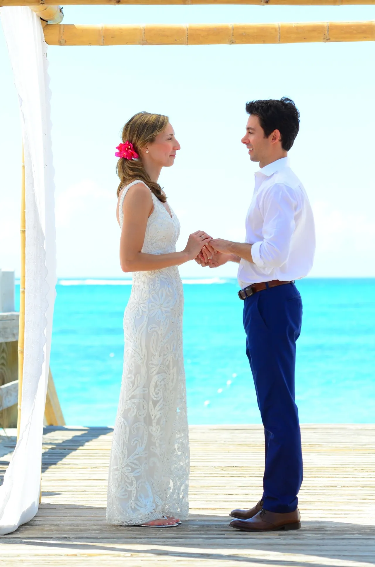 A man and woman holding hands on the beach.