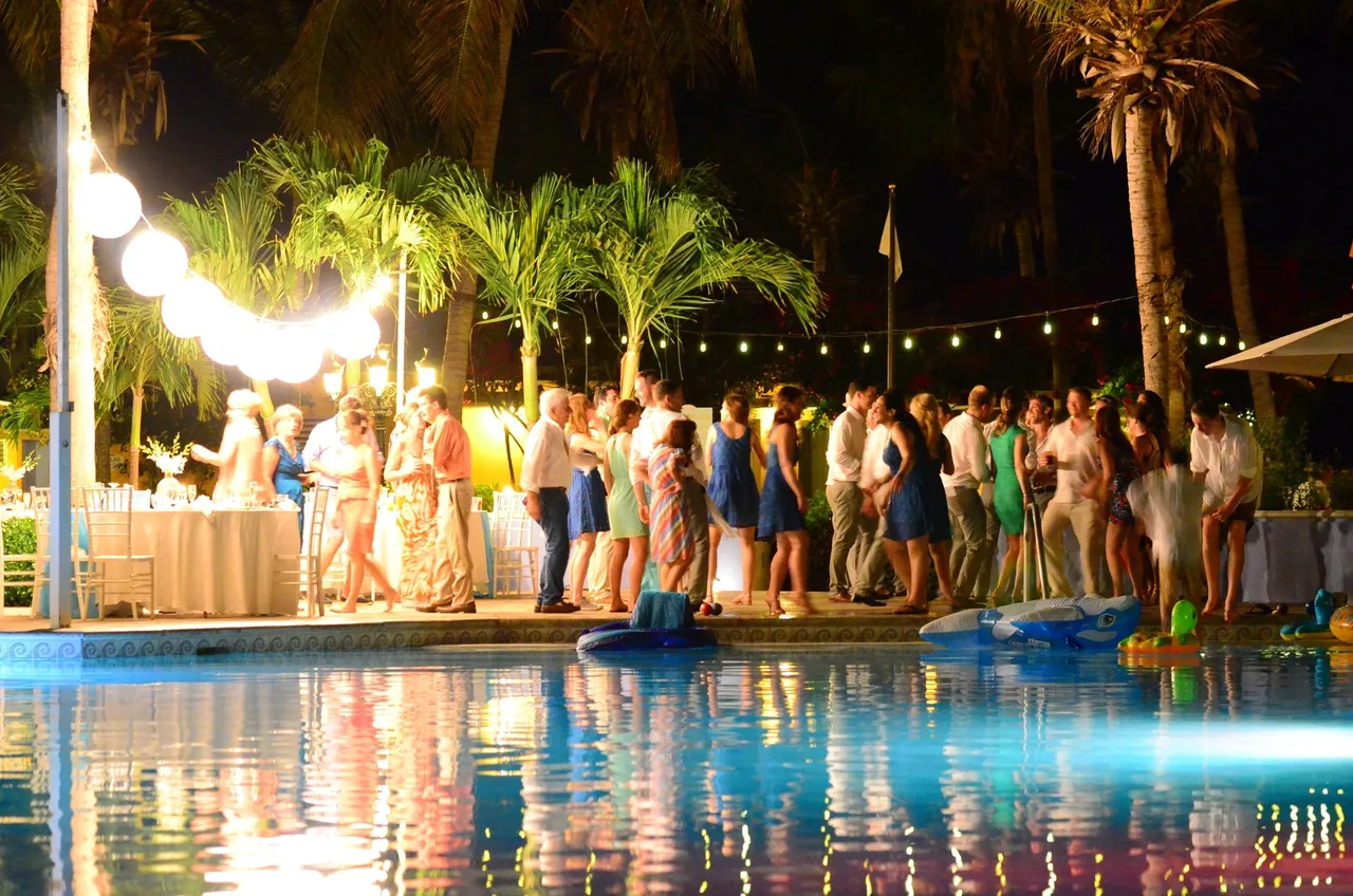 A group of people standing around by the pool.