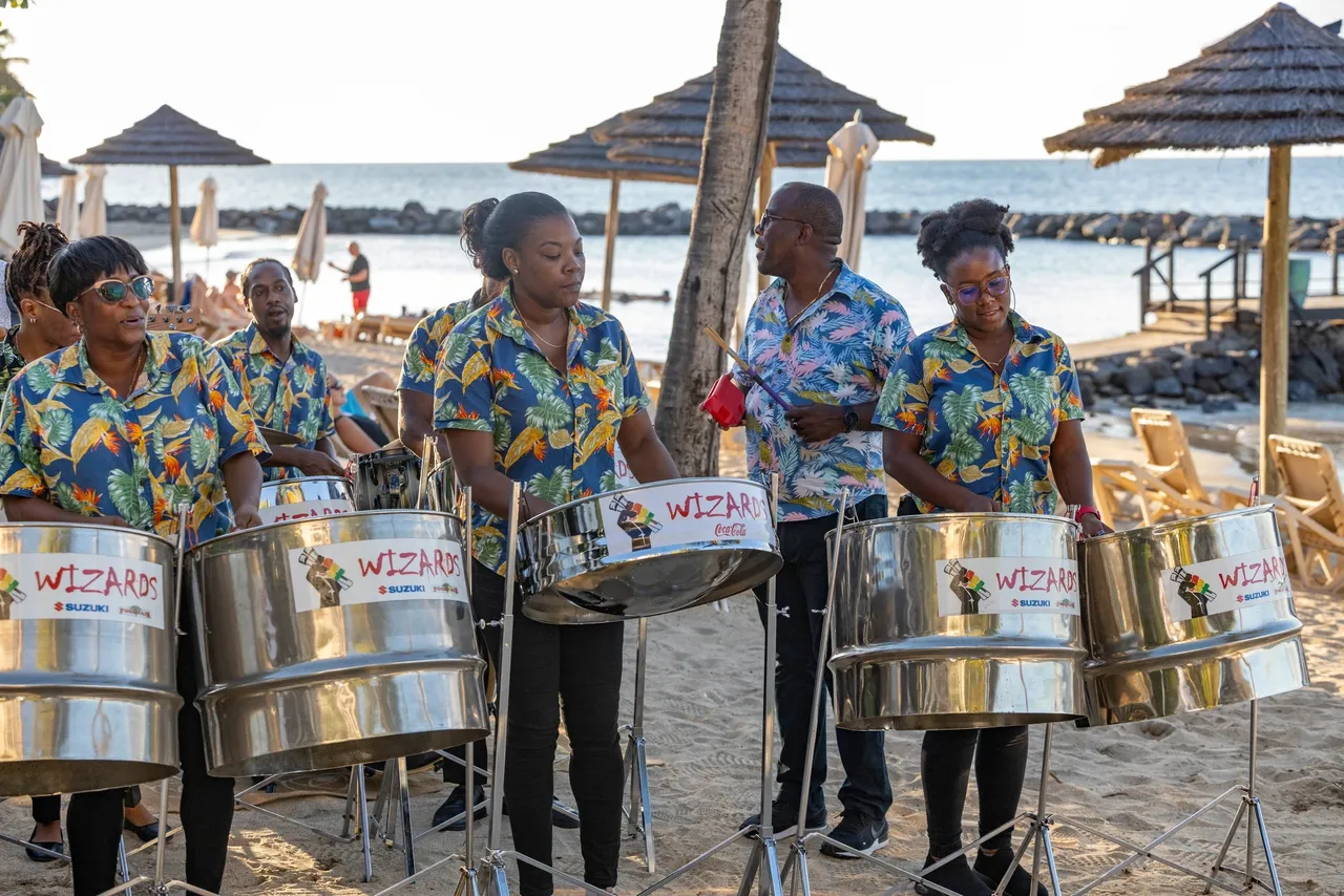 A group of people playing steel drums on the beach.