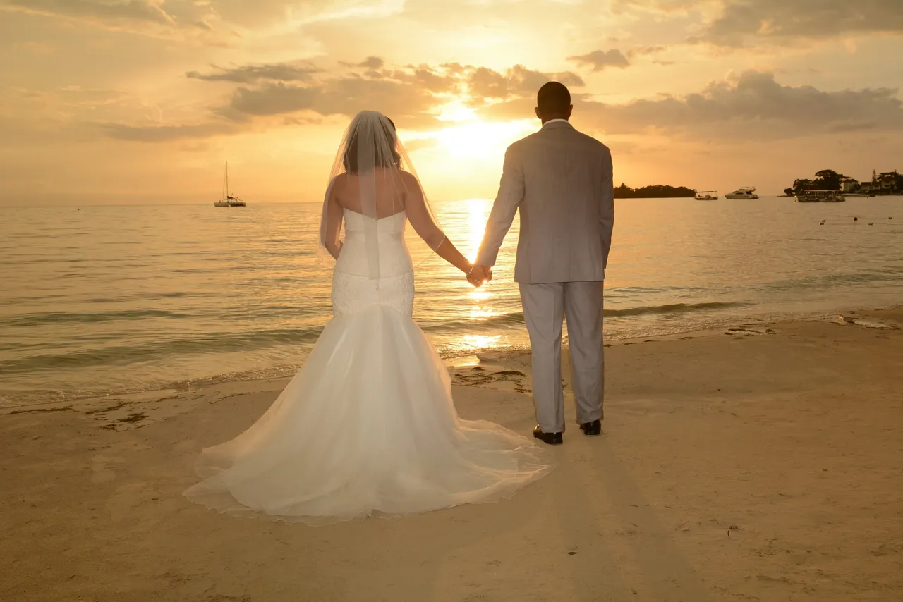 A bride and groom holding hands on the beach