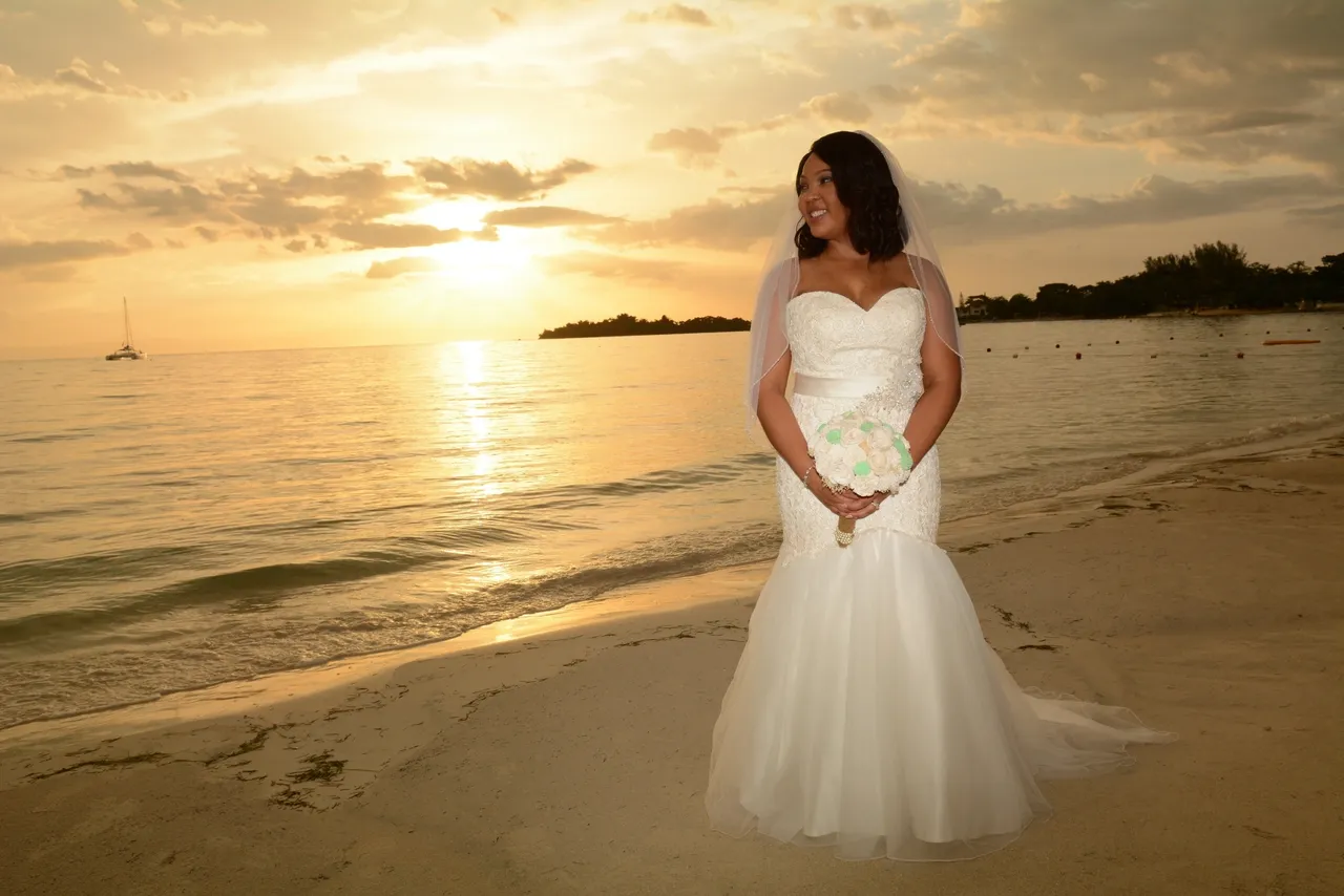 A bride standing on the beach at sunset