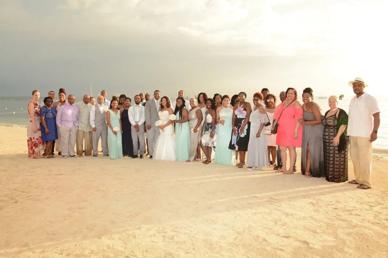 A group of people standing on top of a sandy beach.