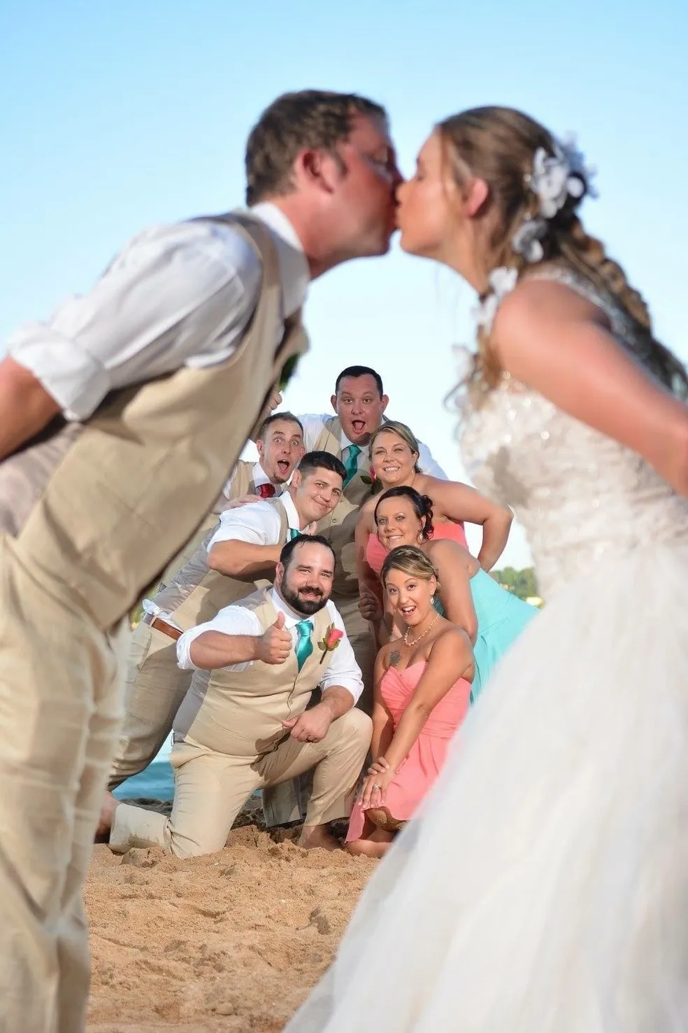 A group of people standing around each other on the beach.