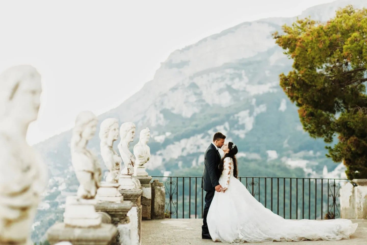 A bride and groom kissing in front of the mountains.