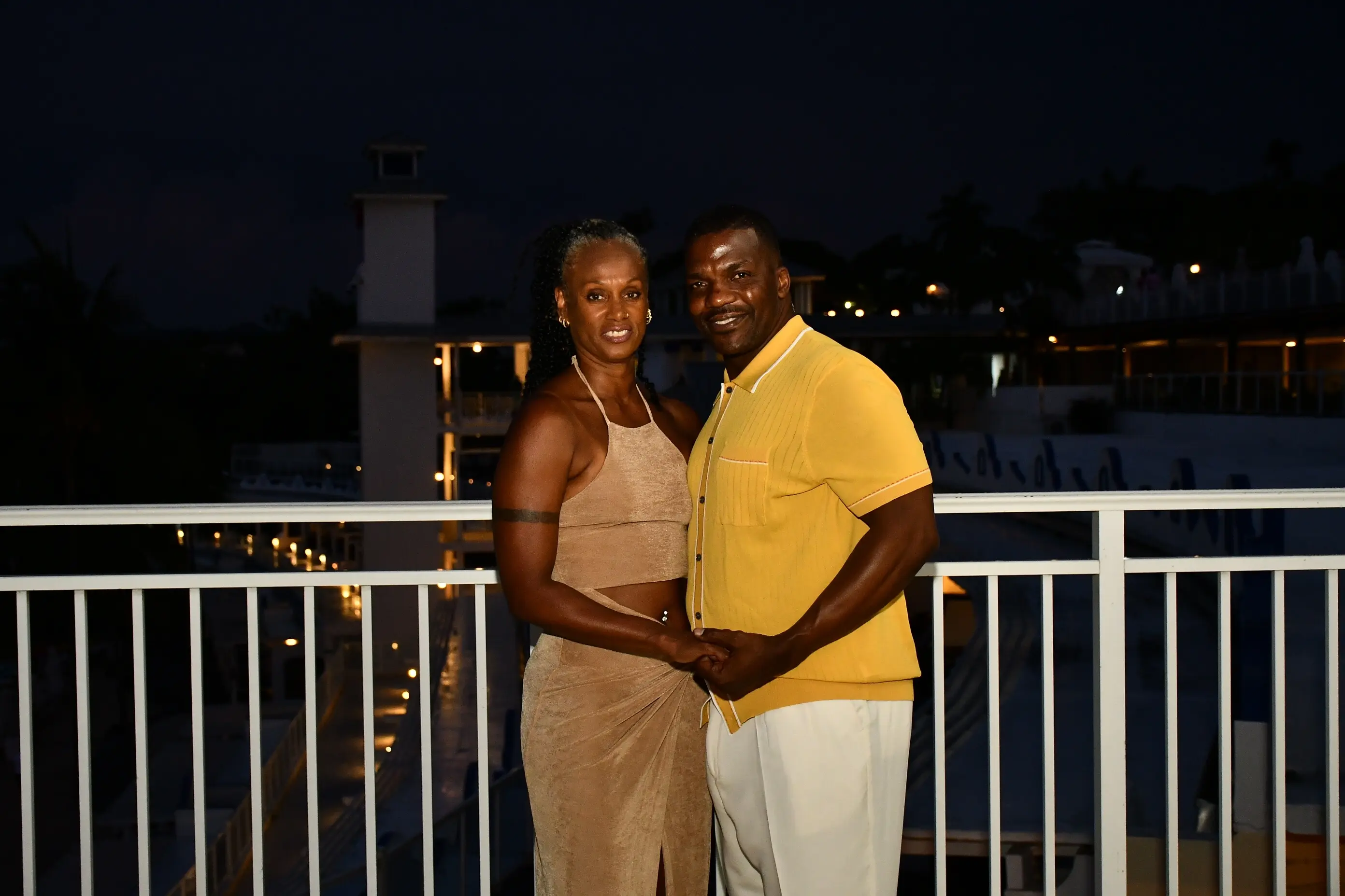 Couple posing on balcony at night.