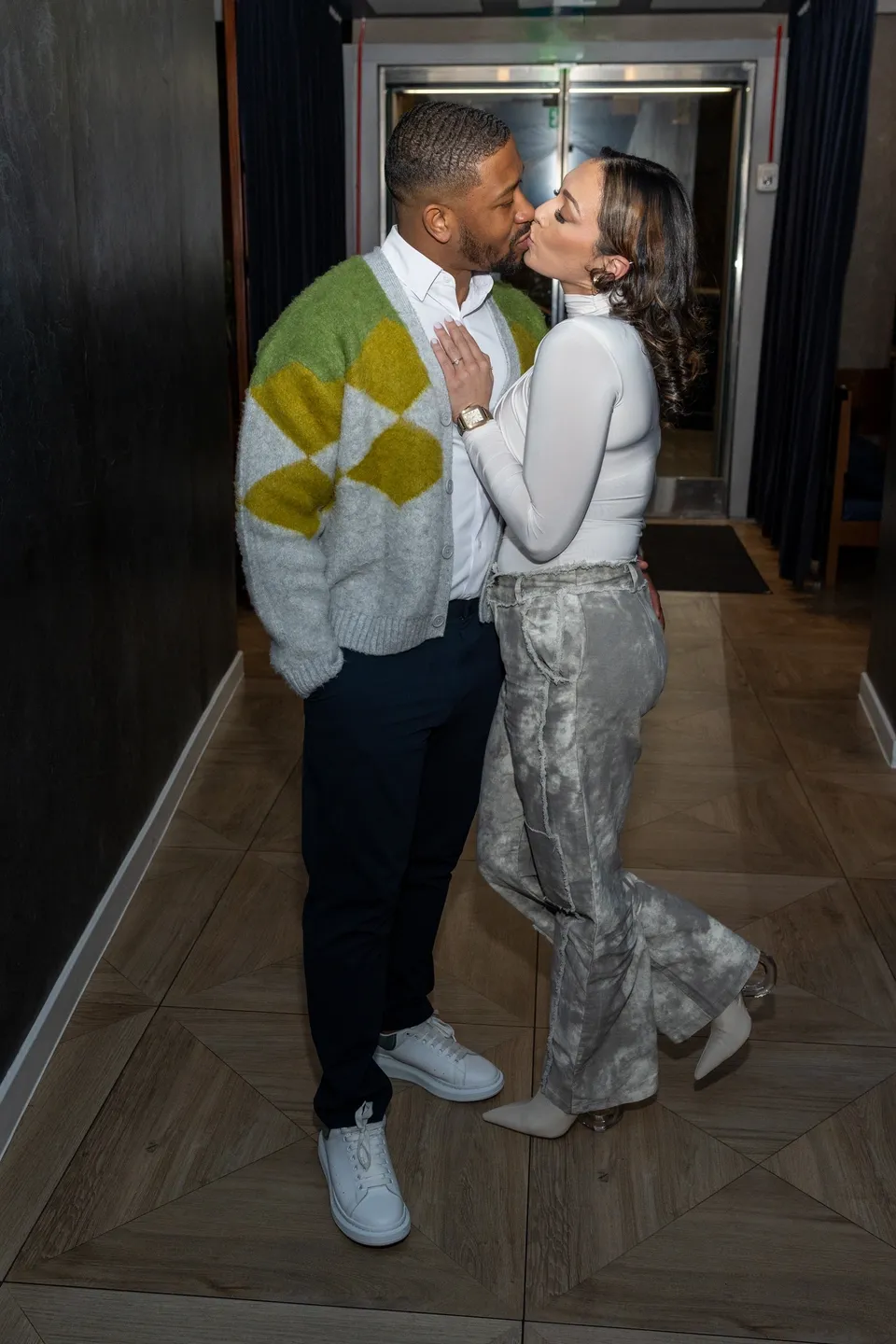 Couple kissing in a hallway.