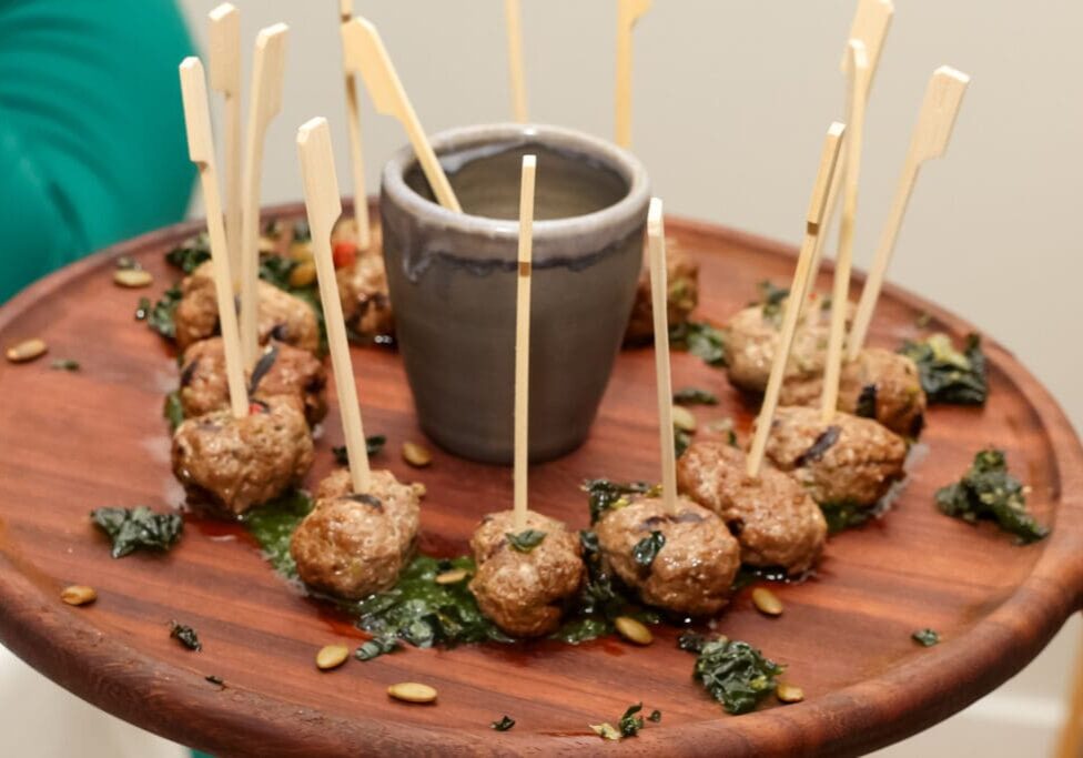 A wooden tray with meatballs and toothpicks on it.